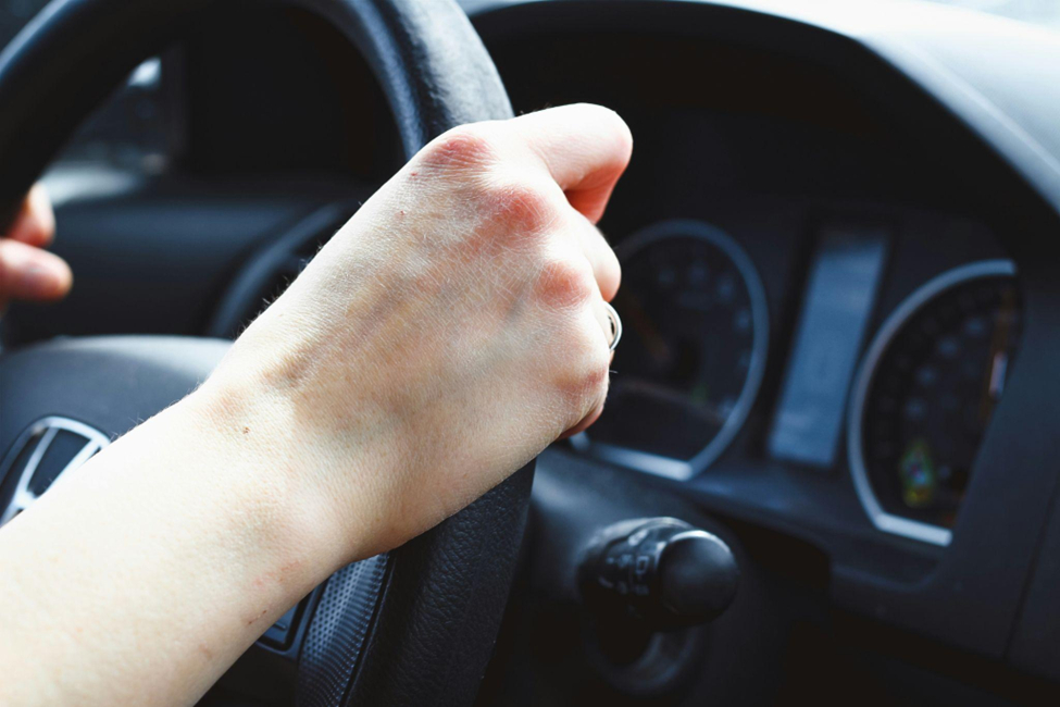 Close-up of a person’s right hand on a steering wheel