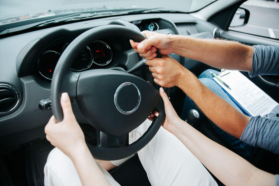 A driving instructor teaches a woman to drive.